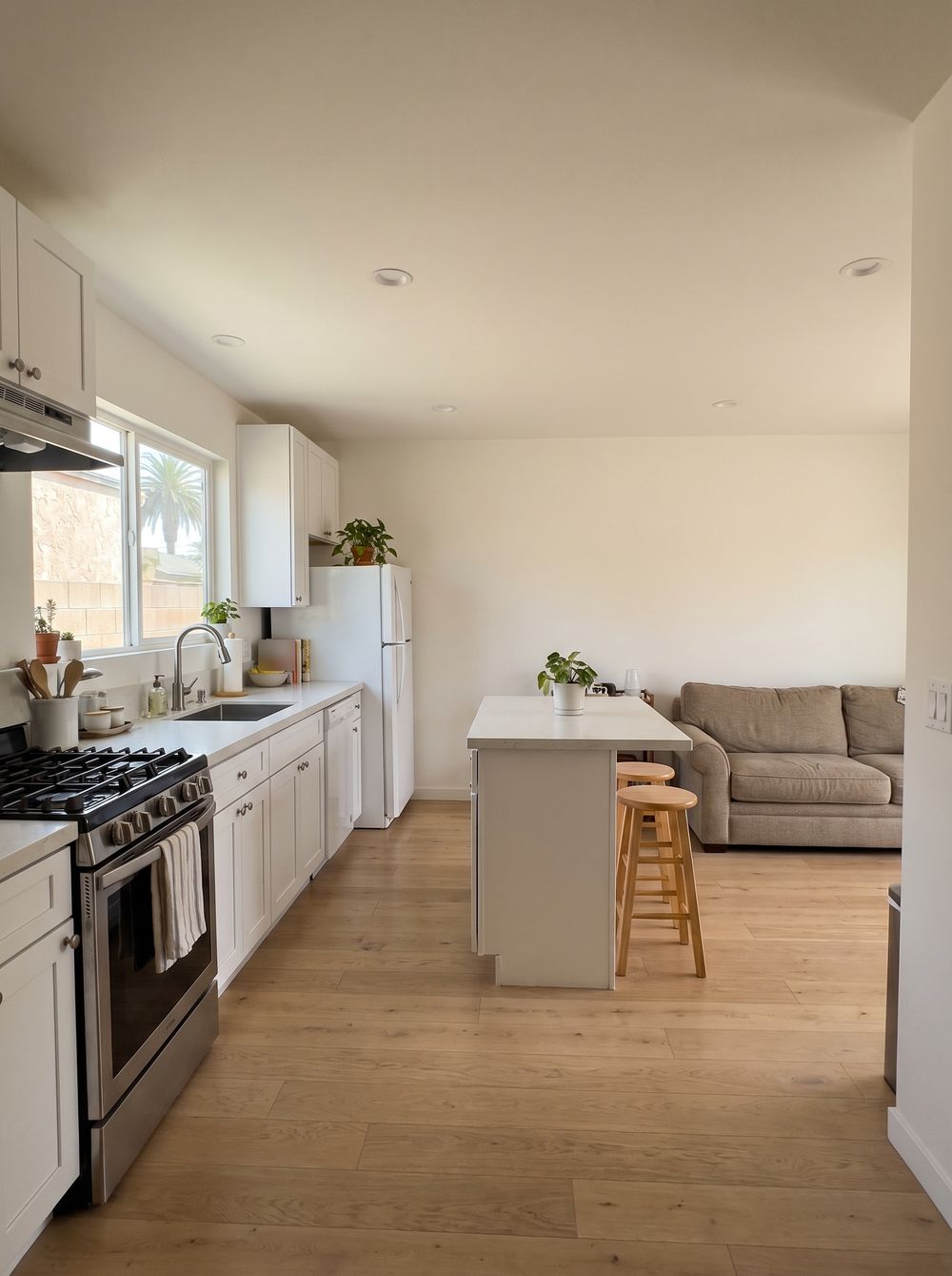 A one-bedroom kitchen with a range, a full-size refrigerator and a small island, with a sofa beyond
